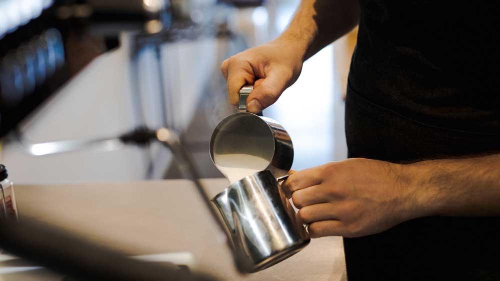 Pouring milk inbetween milk jugs.